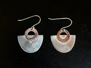 Pair of silver and copper earrings with circular designs on a black background | Jewellery Classes