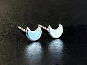 Pair of silver crescent moon-shaped studearrings on a dark surface | jewelry Making products