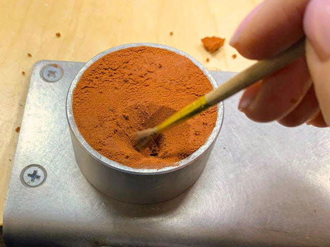 Dusting off loose Delft clay crumbs before pouring molten metal in