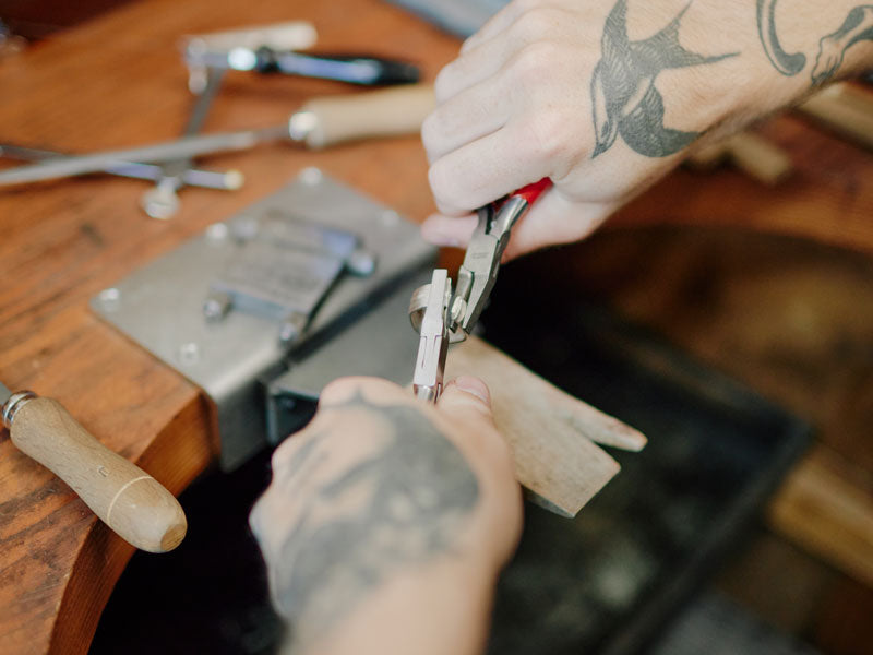 Person using pliers on a wooden workbench with tools | Jewelry Pliers