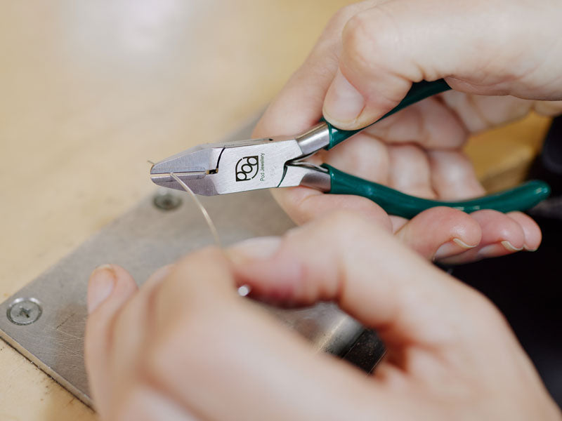 Close-up of hands using flush cutter pliers on a piece of silver wire | Jewellery Tools Australia