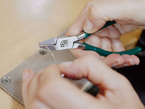 Close-up of hands using flush cutter pliers on a piece of silver wire | Jewellery Tools Australia