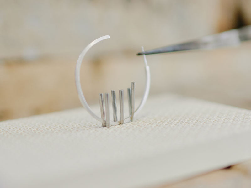 Silver hoop earring on a honeycomb block being held with pins and a third hand | Soldering Supplies