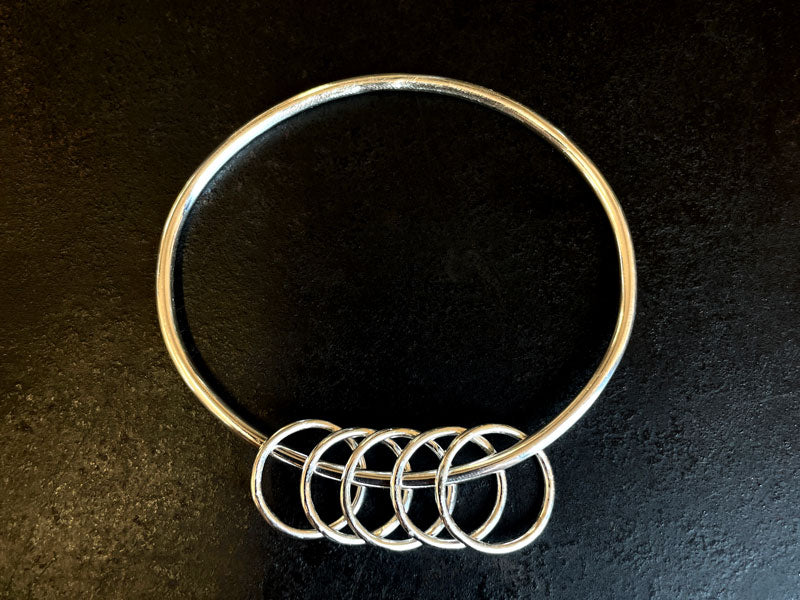 Silver bangle with smaller interlocking rings on a dark background | Jewellery Design
