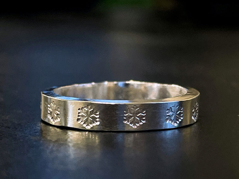 Silver ring with snowflake stamped designs on a dark background | Impressart Stamps