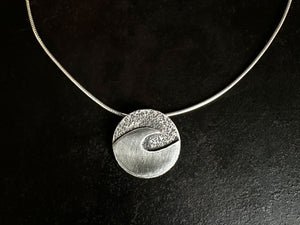 Silver necklace with a sandstone hammer textured wave pendant on a black background | Australian Hammer Supplies