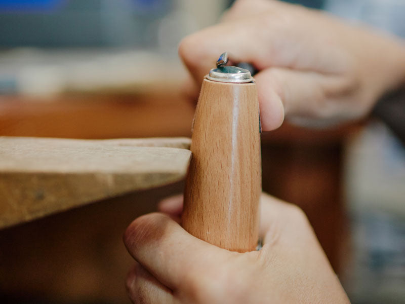 Person holding a wooden ring clamp with a blurred background | Jewellery Making Supplies