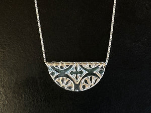 Silver necklace with a half-circle pendant on a black background | Jewellery Design Course