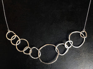Silver necklace with interlocking rings on a black background | jewellery lessons