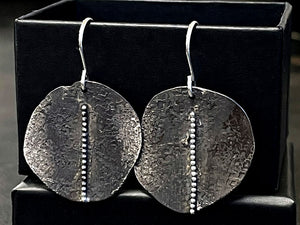 Pair of textured silver earrings on a black stand | jewellery making Classes