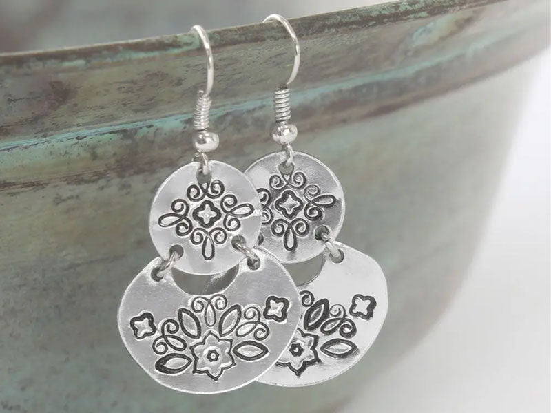 A pair of earrings stamped with Mandala metal stamps in various geometric patterns.