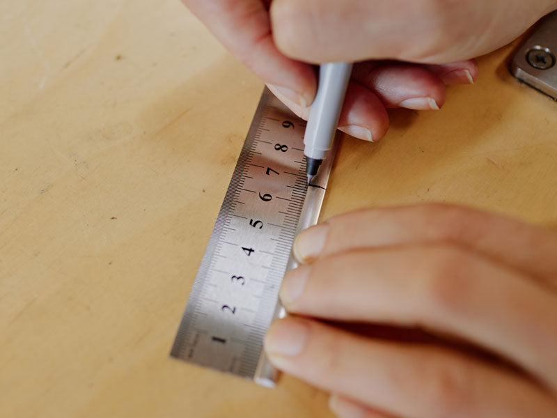 Silver wire being measured with a ruler and marked with a black sharpie | Metal Ruler