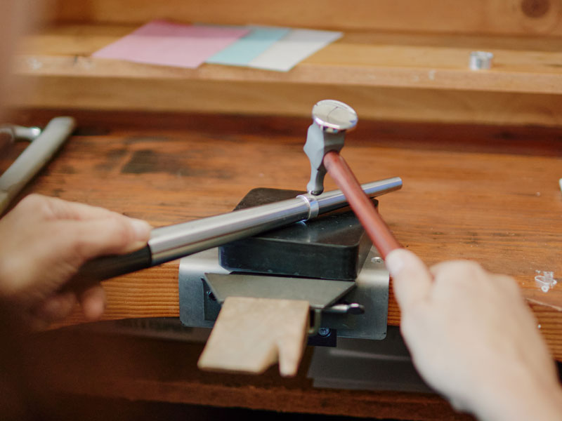 Person using a chasing hammer on a silver ring on an steel ring mandrel on a wooden bench | australian hammer supplies