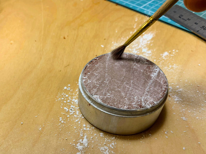 Dusting talcum powder over the Delft clay mould before casting