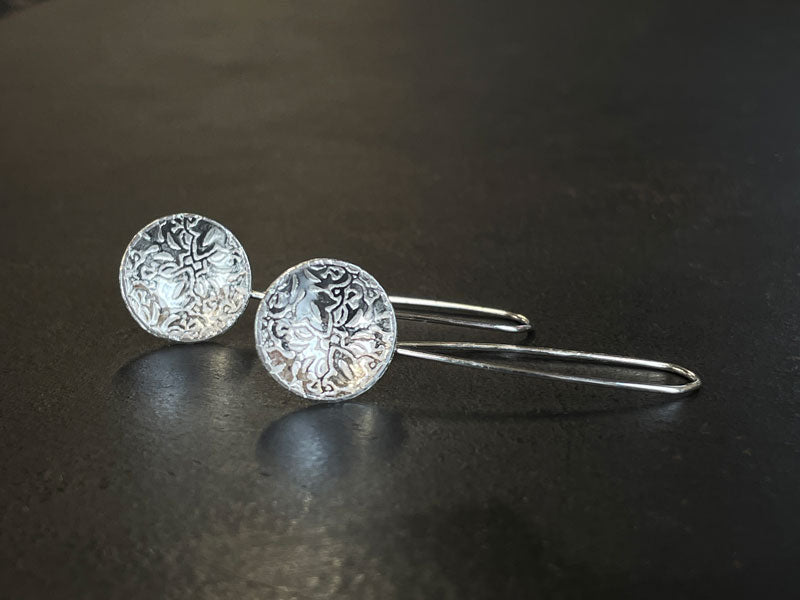 Pair of embossed sterling silver earrings with rolling mill texture on a dark surface | Jewellery Jewellery Making