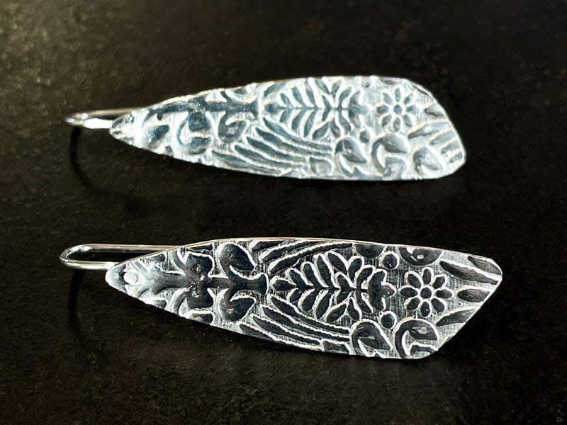 Pair of embossed 925 silver earrings with floral patterns on a dark background | Jewellery Course Melbourne
