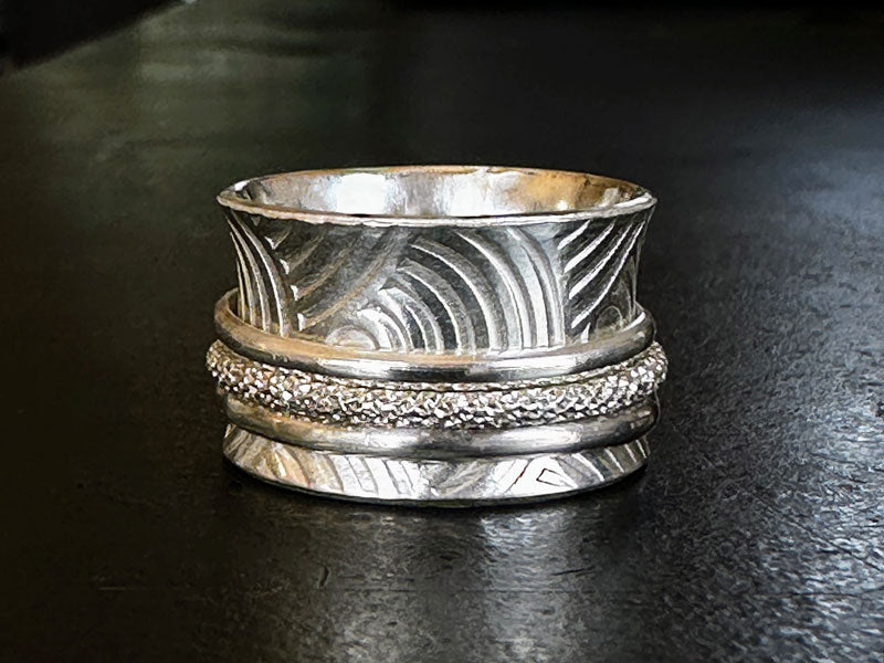 Silver meditation ring with embossed patterns on a dark surface | jewellery australia