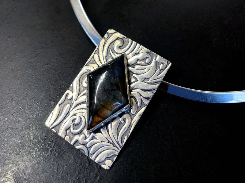 Silver pendant with black stone on a dark background | Stone Setting workshop