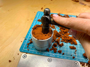 Packing Delft clay firmly into the casting ring frame with a hammer