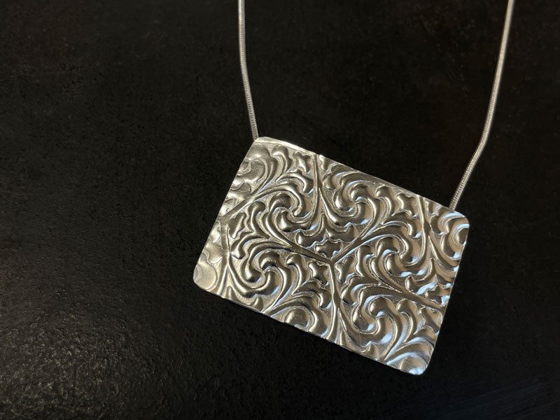 Silver pendant with rolling mill embossed pattern on a black background | wholesale jewellery supplies Australia