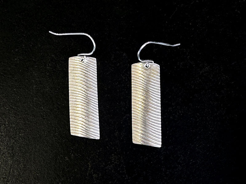 Pair of silver earrings with wavy design on a black background | Jewellery Classes