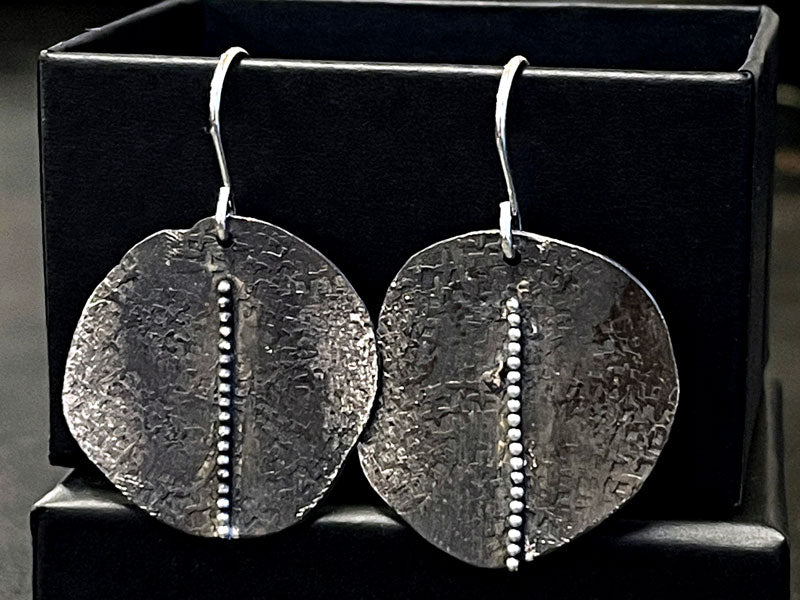 Pair of textured silver earrings on a black stand | jewellery making Classes