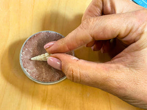 Pressing a shell design into Delft clay to form a sand casting mould